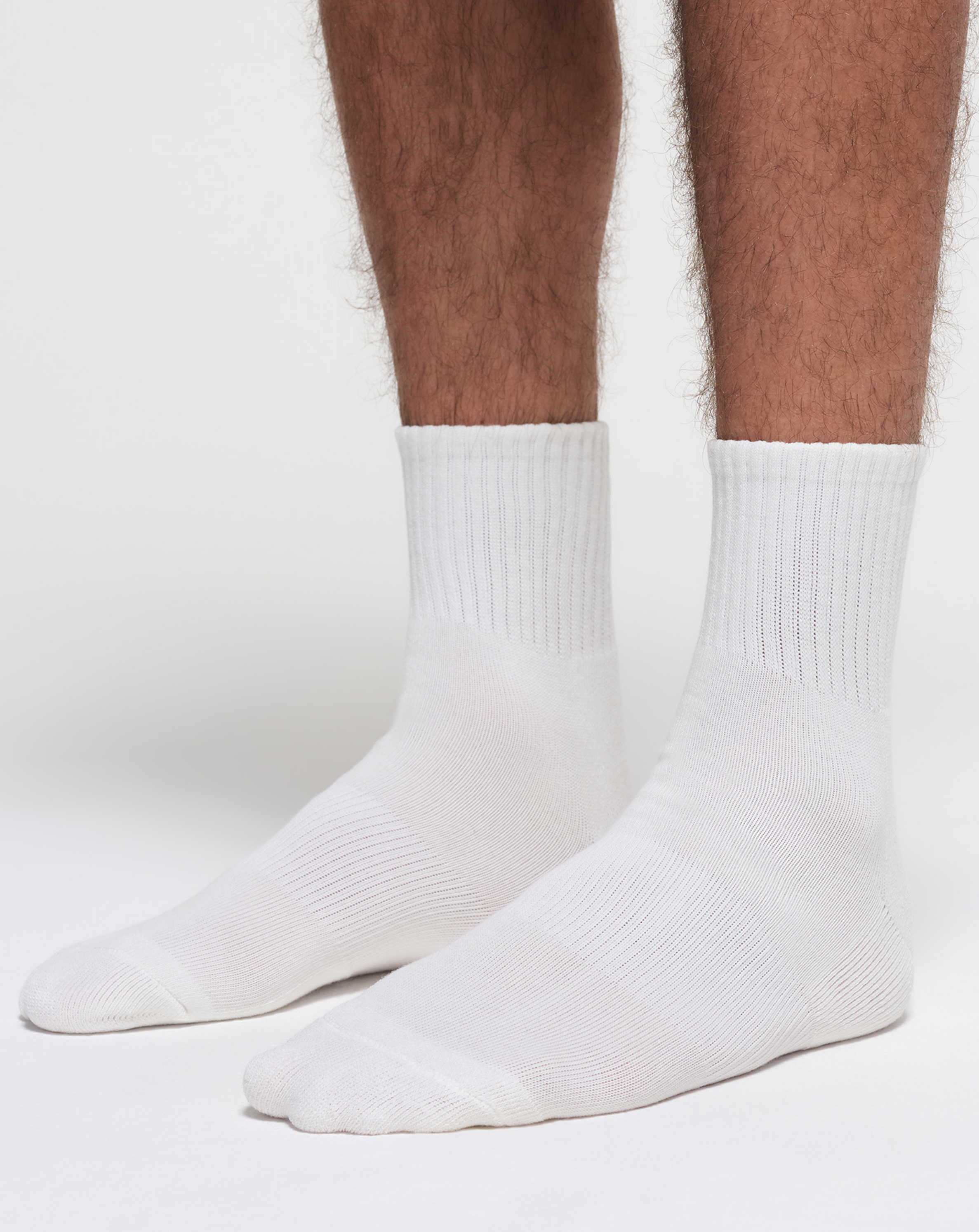 A MODEL POSES WEARING SKIMS MENS LOUNGE SOCKS