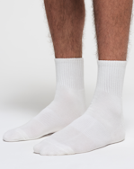 A MODEL POSES WEARING SKIMS MENS LOUNGE SOCKS