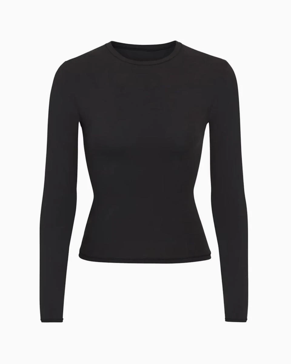A MODEL POSES WEARING SKIMS LONG SLEEVE T-SHIRT