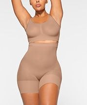 A model wears the EVERYDAY SCULPT HIGH-WAISTED MID THIGH SHORT