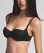 A model poses wearing SKIMS Ultimate Bra in cocoa