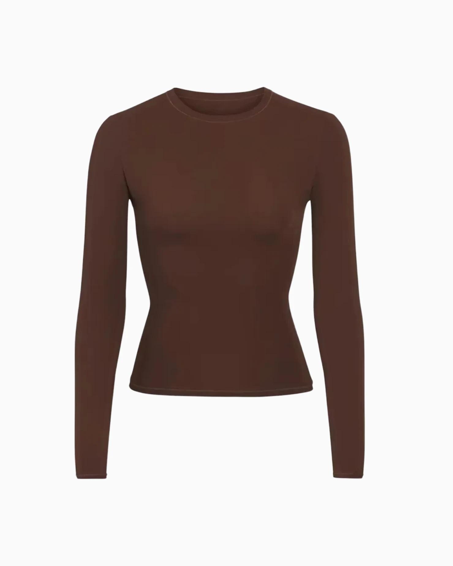 A MODEL POSES WEARING SKIMS LONG SLEEVE T-SHIRT