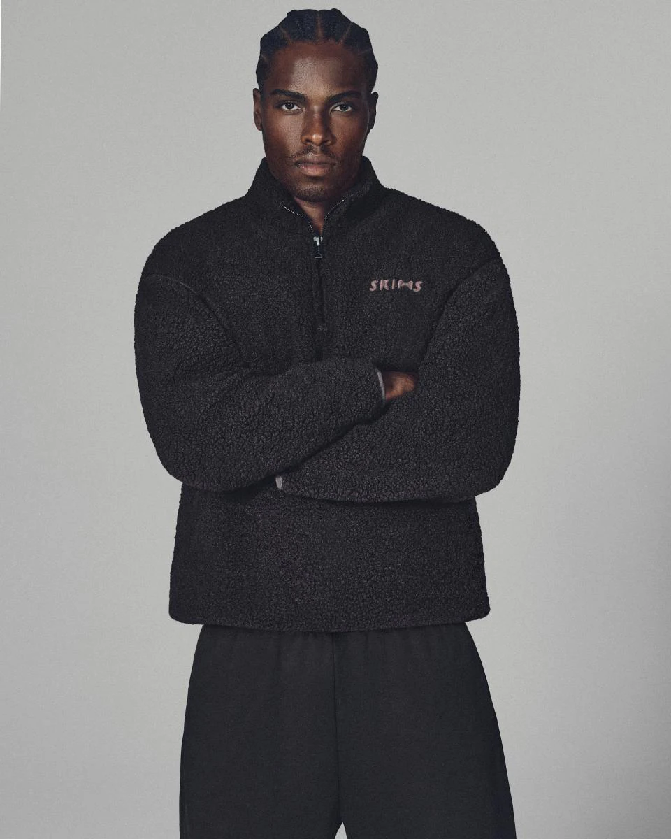 A MODEL POSES WEARING SKIMS MENS SPORT