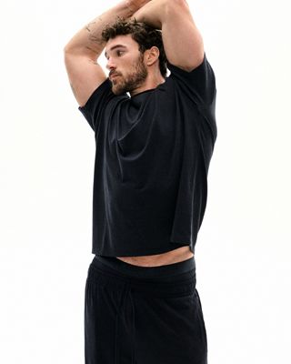 A MODEL POSES WEARING SKIMS MENS SPORT