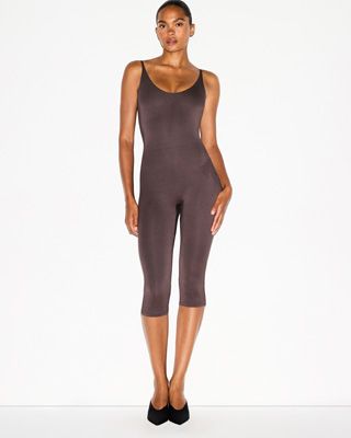 A MODEL POSES WEARING SKIMS CATSUITS & ONESIES