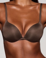 A model poses wearing SKIMS Ultimate Bra in cocoa