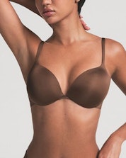 A model poses wearing SKIMS Ultimate Bra in cocoa