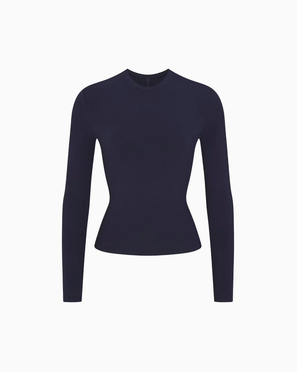 A MODEL POSES WEARING SKIMS LONG SLEEVE T-SHIRT