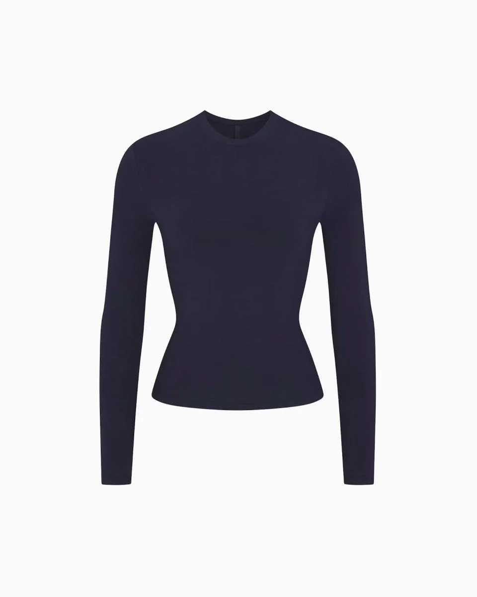 A MODEL POSES WEARING SKIMS LONG SLEEVE T-SHIRT