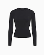 A MODEL POSES WEARING SKIMS LONG SLEEVE T-SHIRT