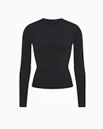A MODEL POSES WEARING SKIMS LONG SLEEVE T-SHIRT